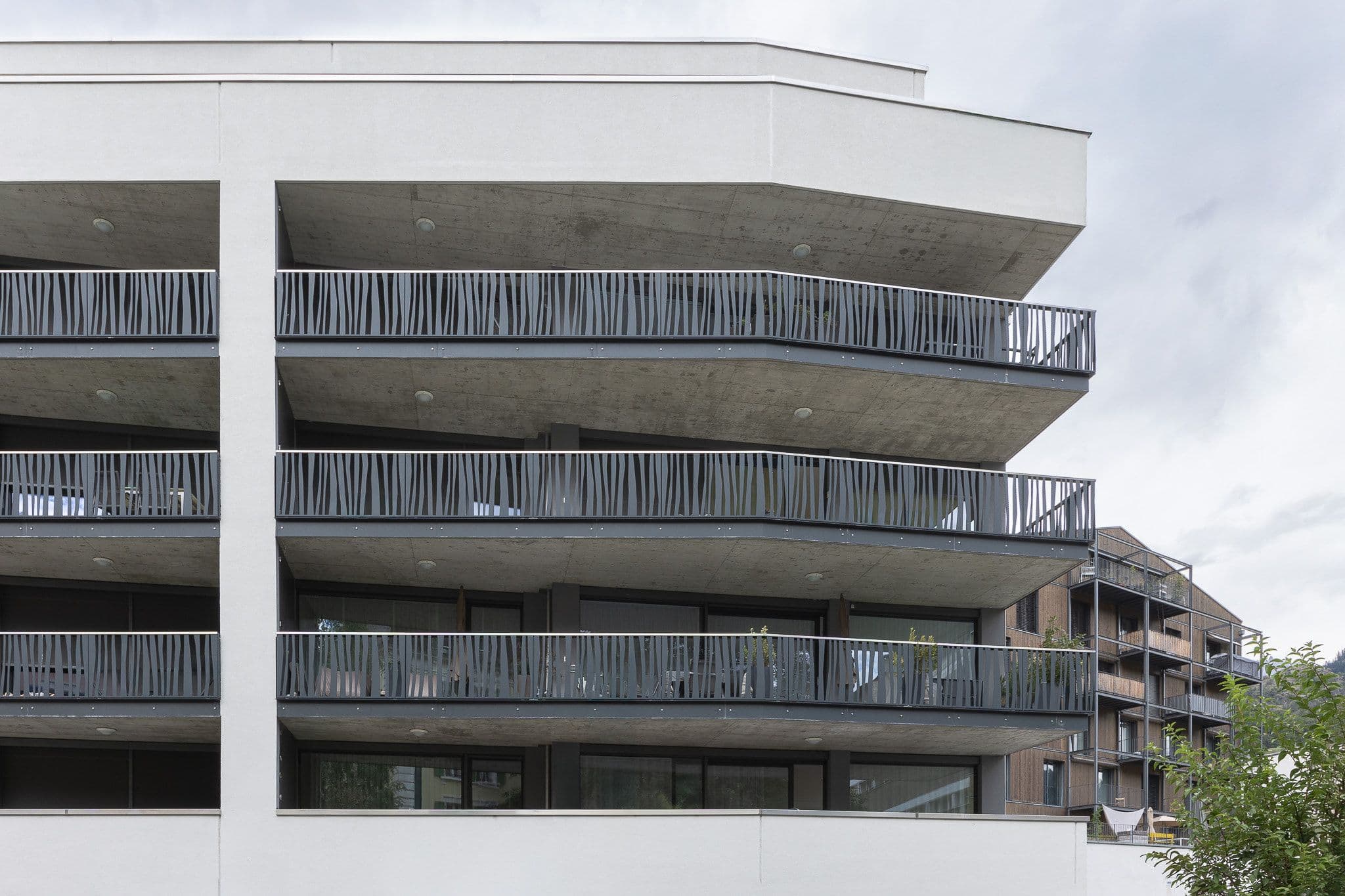 Aussenansicht des MFH Mühleweg in Naters mit Fokus auf die Balkone mit gemusterten Geländer.