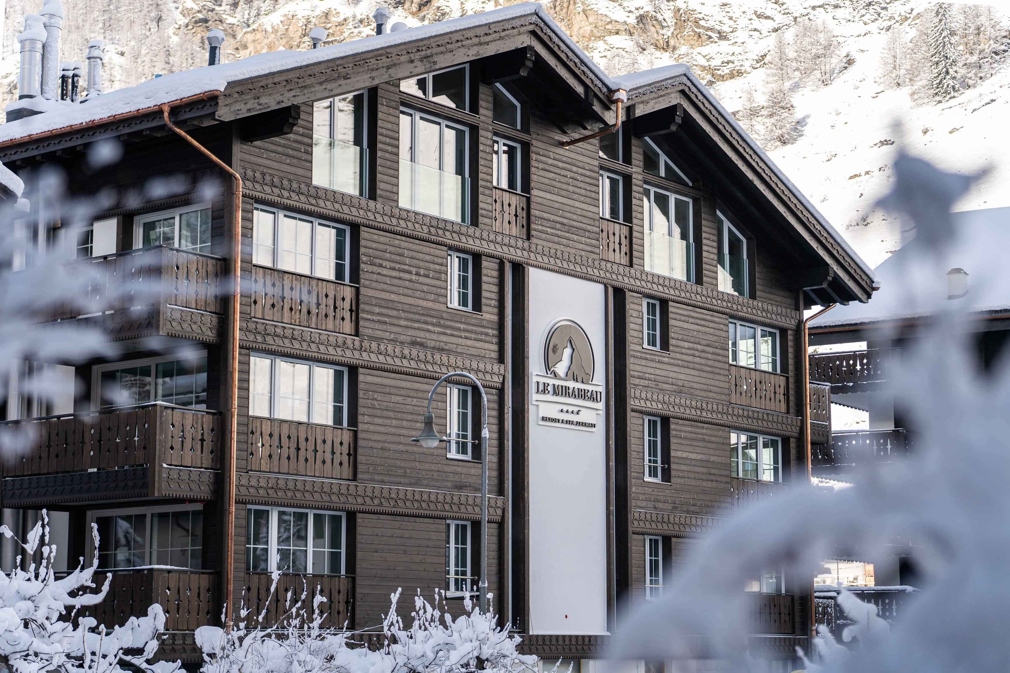 Aussenansicht im Winter des Le Mirabeau Chalet Etoile in Zermatt. Dunkle Fassade aus Holz sowie weisse verputzte Wände